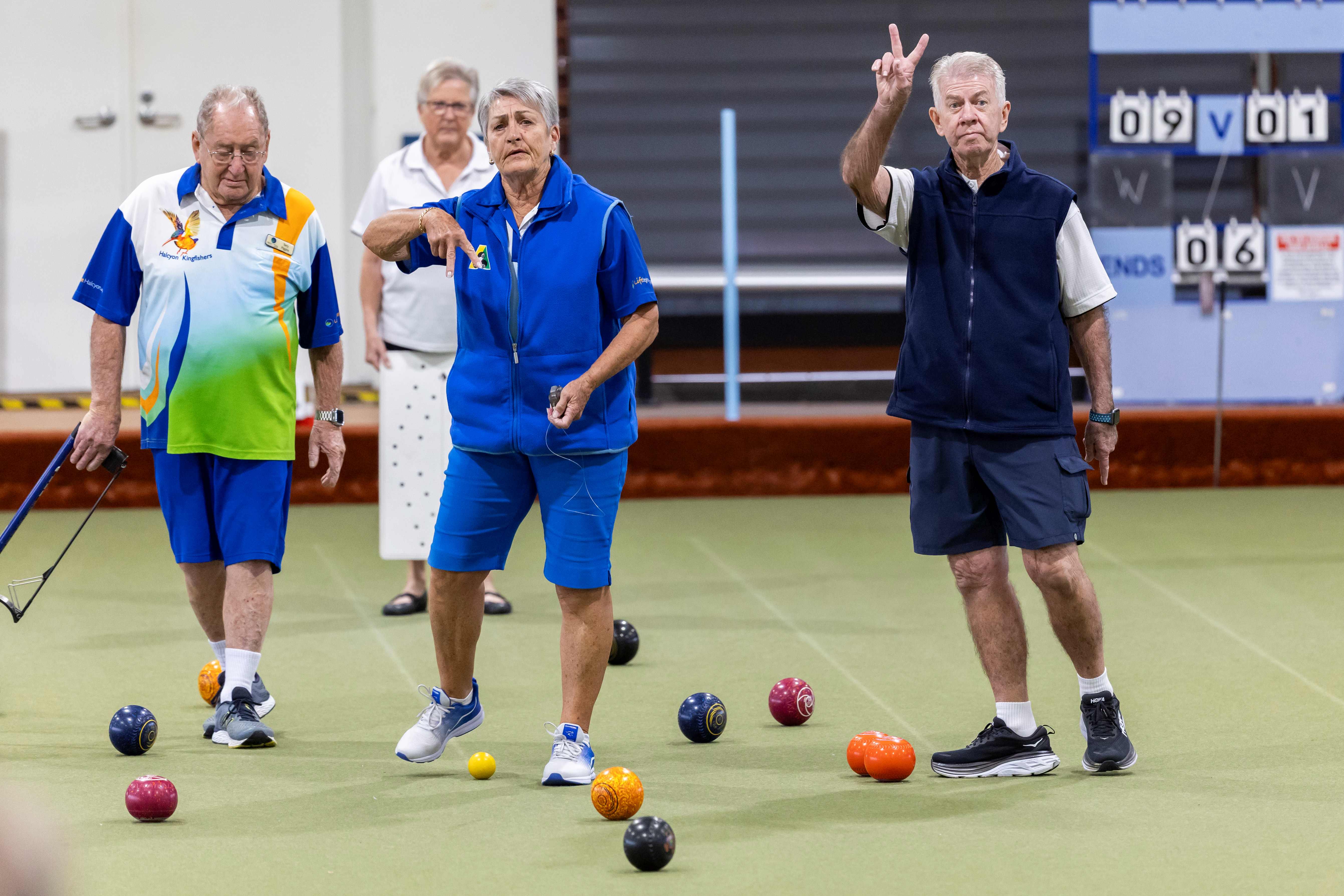 A woman and two men showing fingers up and down to denote scores