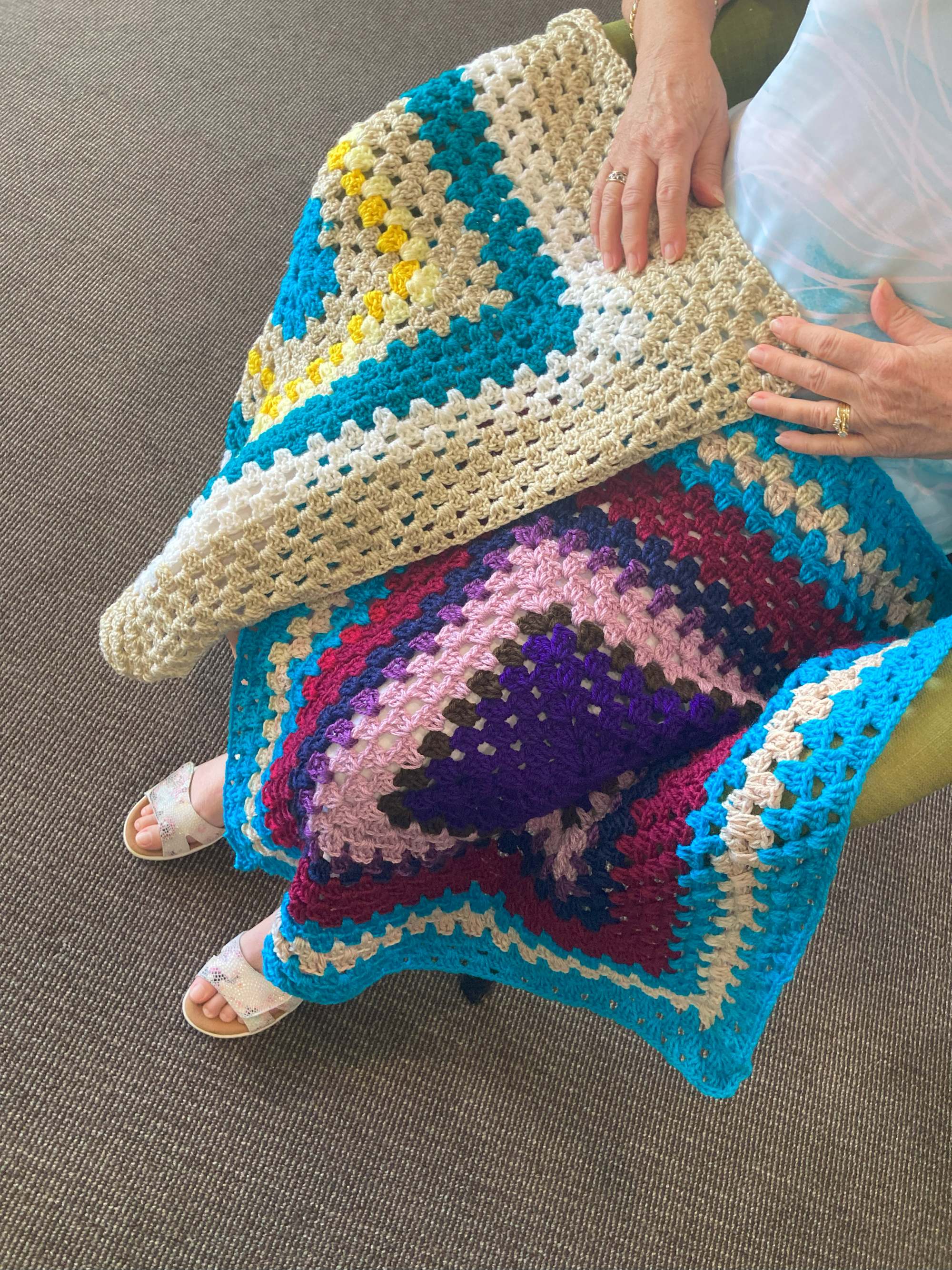 Two crocheted knee blankets on someone's lap