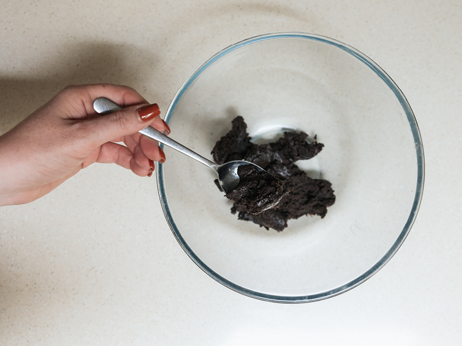 A clear mixing bowl with blended Oreo cookies and cream cheese.