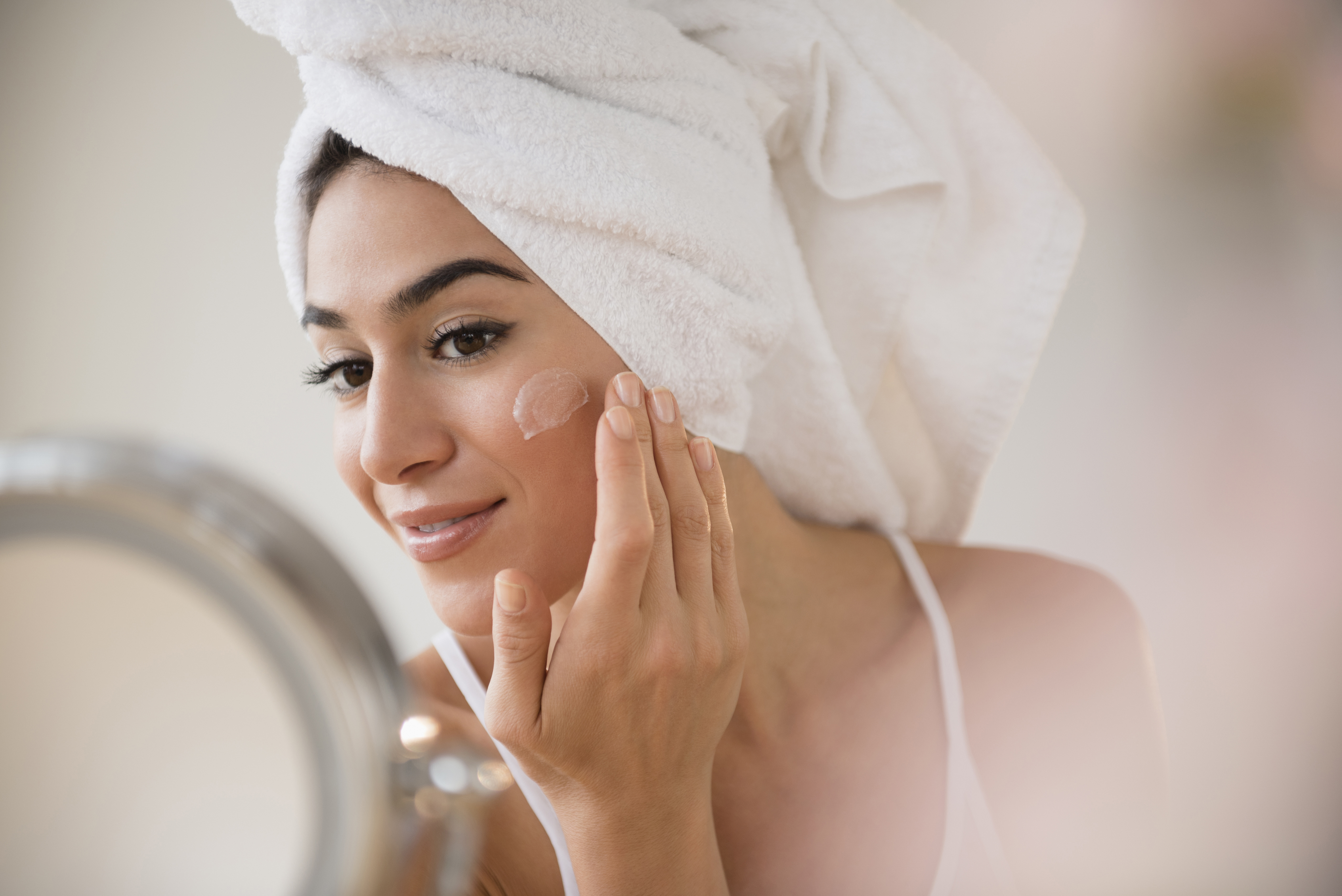 Beauty Bliss. Woman in hair wrap applying a face mask.