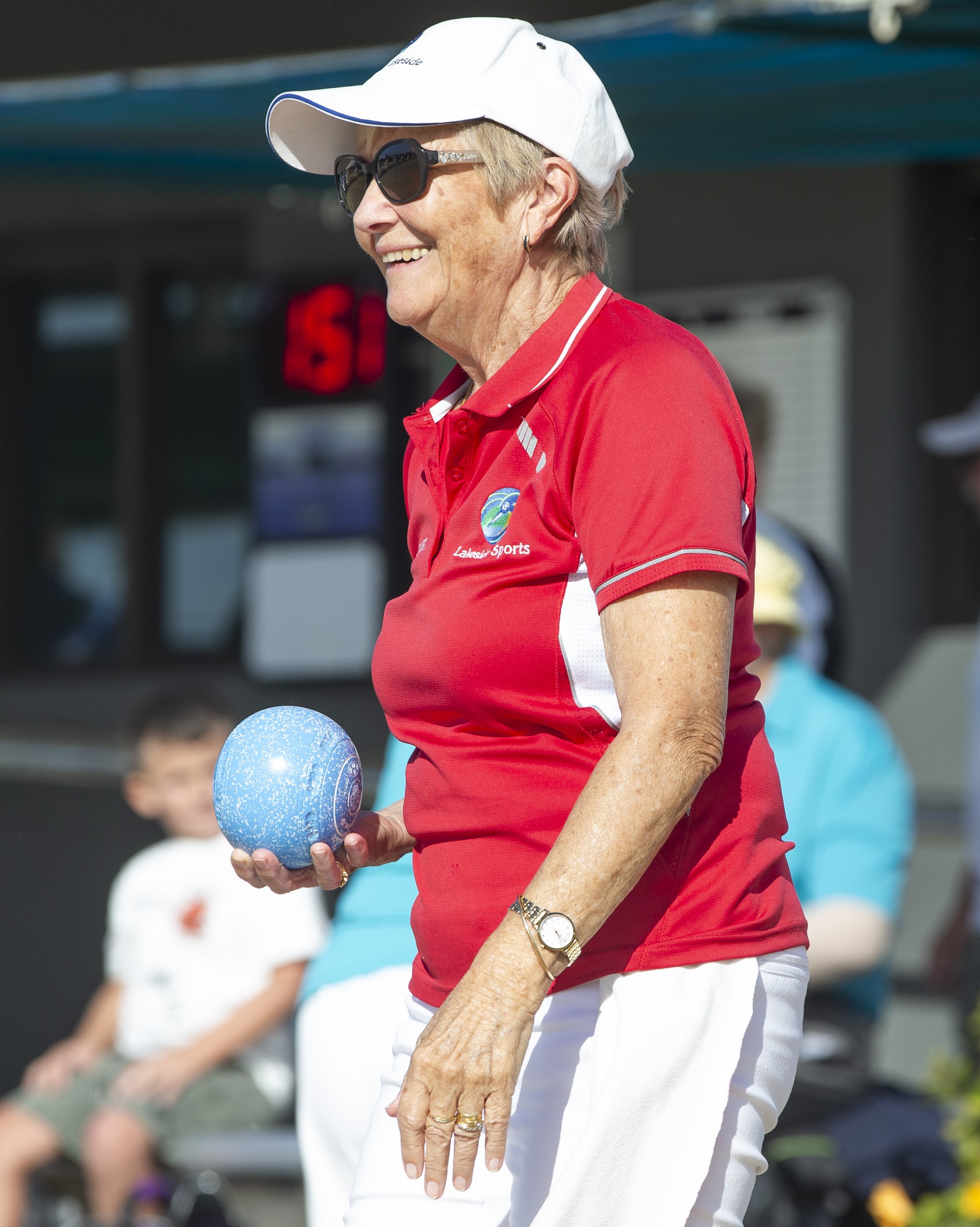 Woman in red shirt and white hat holding a bowl and smiling