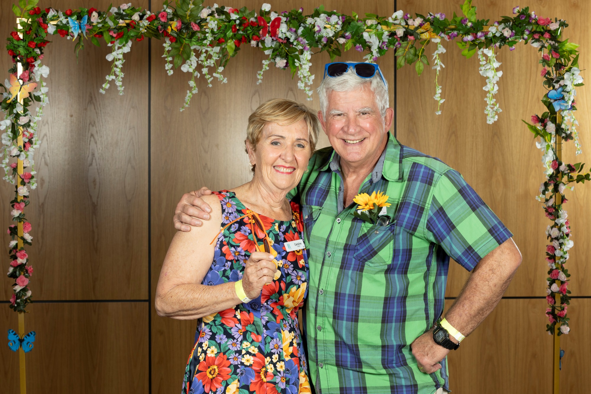 A couple holding each other standing in front of a flower arch