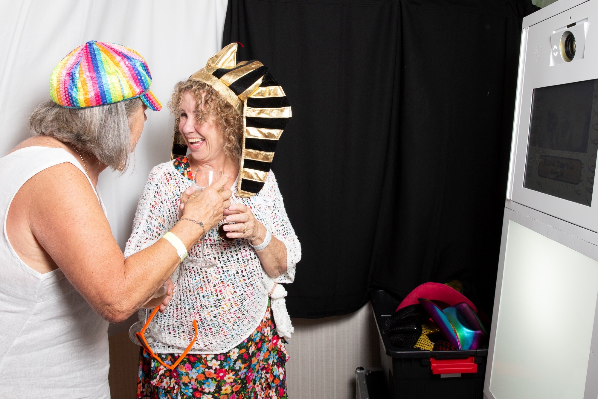 Two women in a photo booth dressed up in fancy dress items