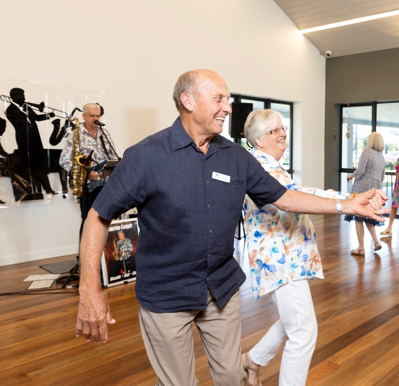 Couple dancing with a saxophone player on the stage behind them