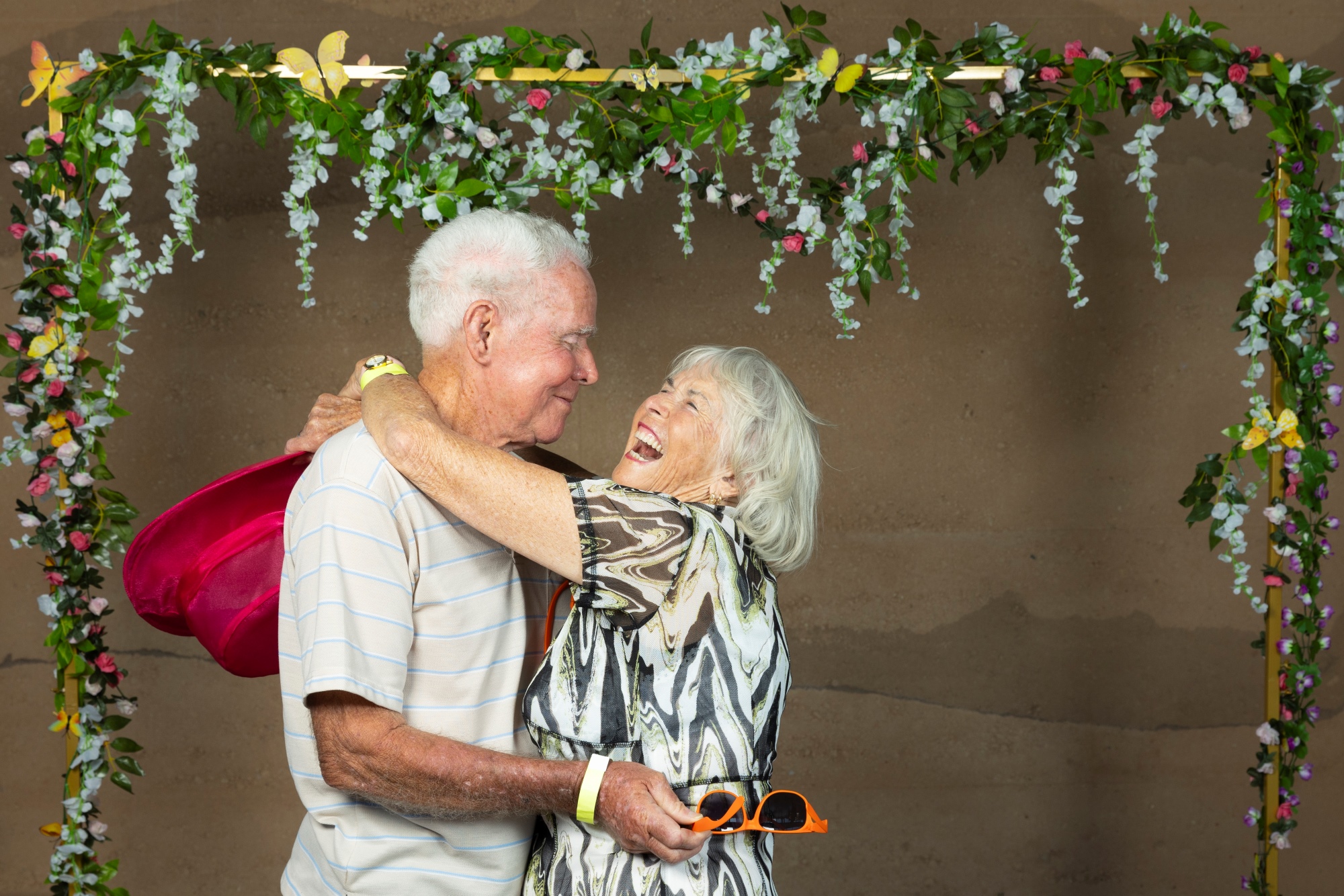 Happy home owners with their arms around each other in front of a flower display