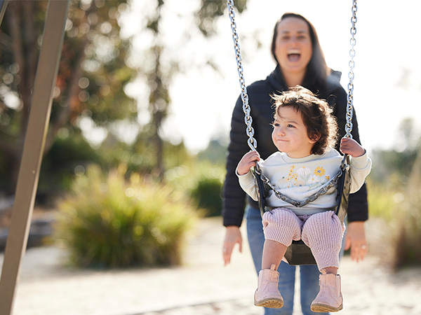 Mother and daughter on swing set. 