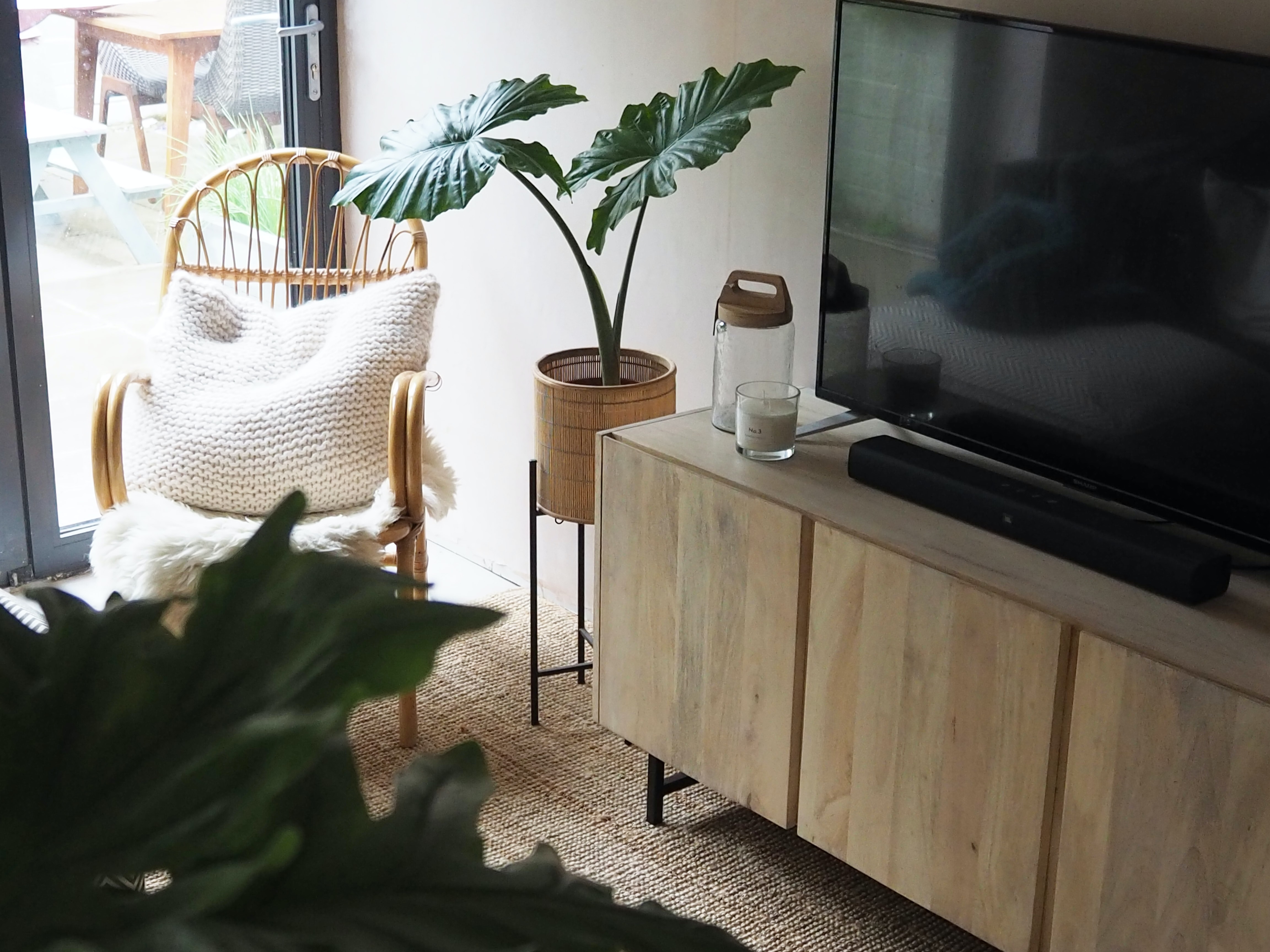 rattan chair, tv cabinet and tv on natural rug