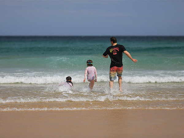 Father and two daughters playing at beach. 