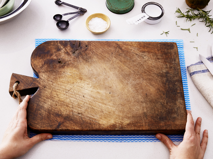 A damp cloth is placed under a cutting board to avoid slipping