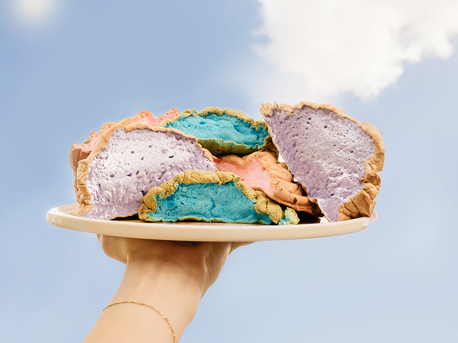 Cloud bread held up high on a plate by someone's hand.