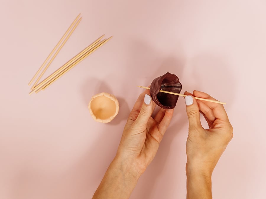 Skewers poking a hole into polymer clay pot for drainage