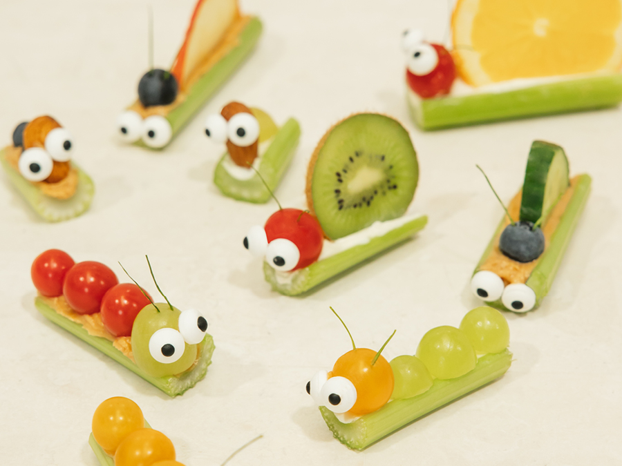 An assortment of caterpillars, snails and ants made out of celery, grapes, kiwi fruit, and almonds. 