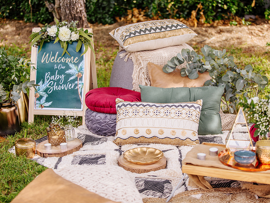 Pillows, blankets and serving ware are set up for an outdoor picnic 